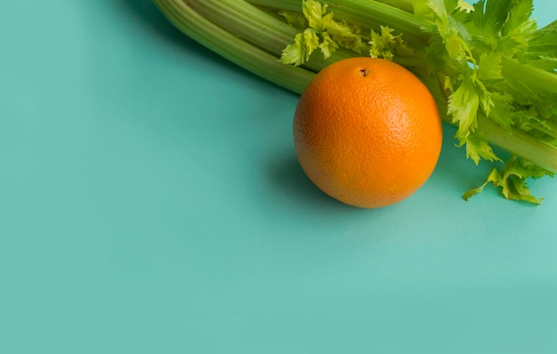 orange and celery on blue background