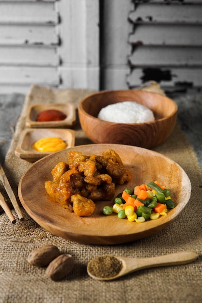 Orange chicken with mixed vegetables on wooden plate