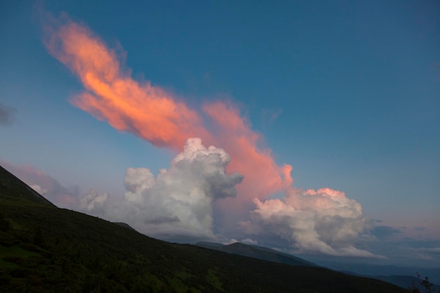 山の日没時の夕方の光の中でオレンジ色の巻積雲と積雲