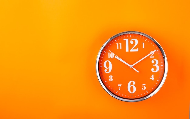 Photo orange clock on orange background