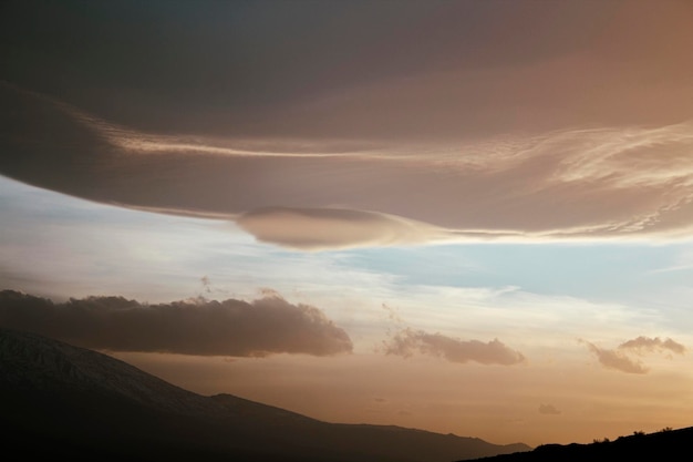 日没時の山の上のオレンジ色の雲