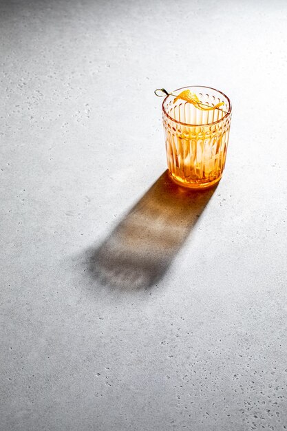 Orange cocktail in glass with light shadow isolated on concrete table