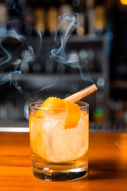 Orange cocktail with ice cube and orange zest.