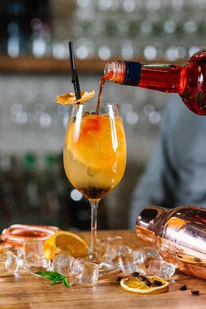 Orange cocktail with lemon and ice in glass at the bar background