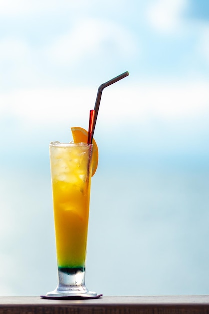 Orange cocktail with orange slide on wooden table with blue sky background