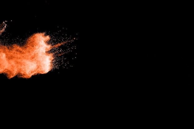 Orange color powder explosion on black background.