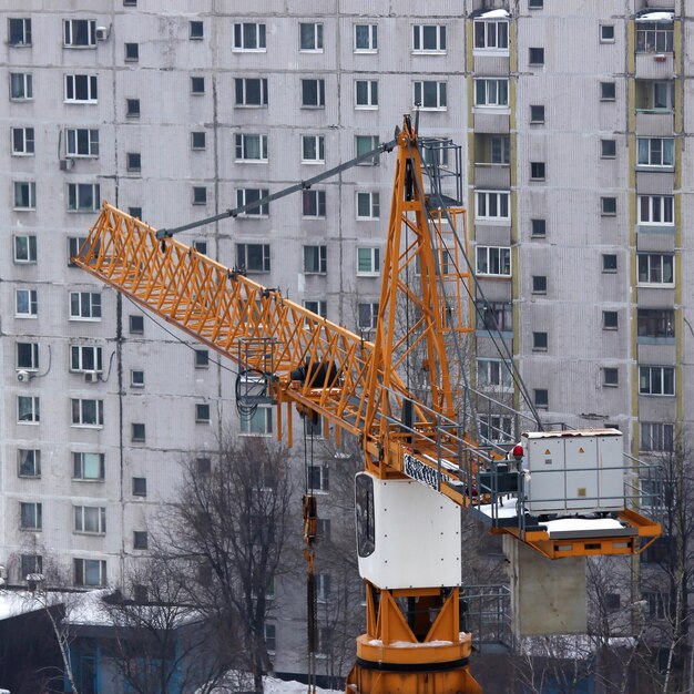 Оранжевый строительный кран возле дома