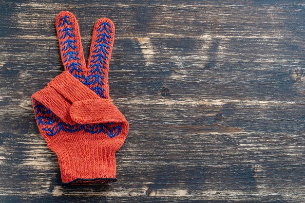 Orange construction gloves shows victory sign on wooden background top view copy space