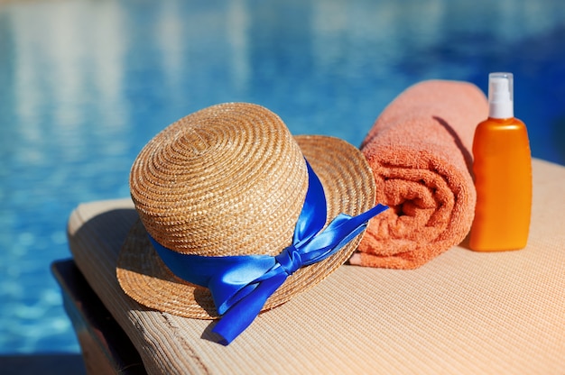 Orange cotton towel and sunscreen body lotion and hat in a orange tube