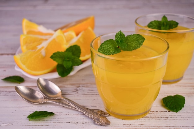 白い木製の背景にグラスにオレンジ クリーム (英語の柑橘系のクリーム)。