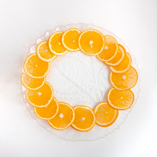 An orange cut into circles lies on a transparent plate.