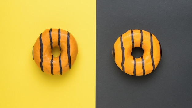 Orange donuts glazed with chocolate on a yellow and black background. Delicious popular pastries.