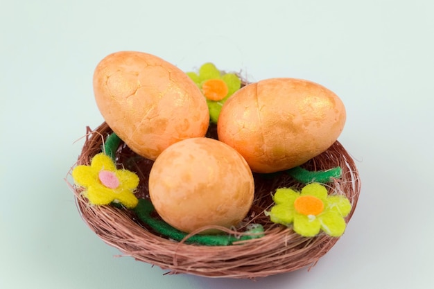 Orange Easter eggs in a nest on a pale green background