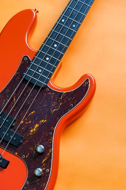 Photo orange electric bass guitar on orange background with copy space