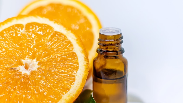 Orange essential oil in a bottle and oranges