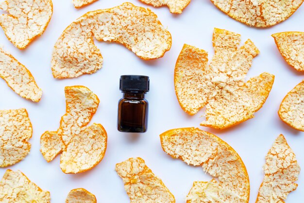 Orange essential oil with orange peel on white background