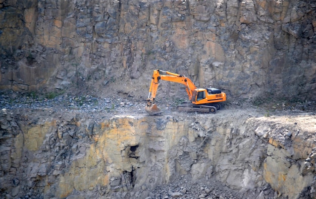 Orange excavator, digger in a granite quarry