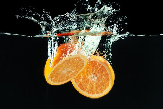 Orange falls into the water and making splashes