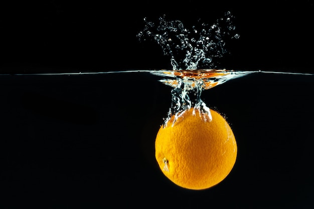 Orange falls into the water and making splashes