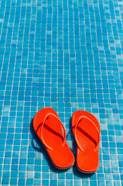 Orange flip flops in the swimming pool.