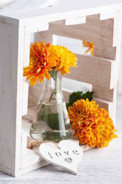 Orange flowers in glass pot on rustic table