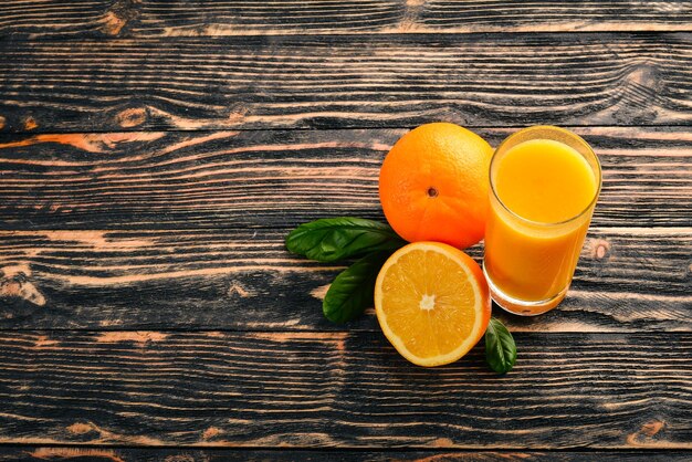 Orange fresh juice and oranges on a wooden surface Top view Free space for text