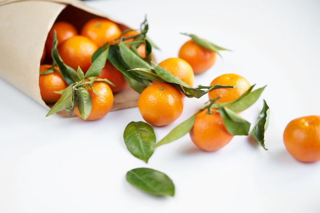 Orange fresh tangerines with green leaves in a paper bag