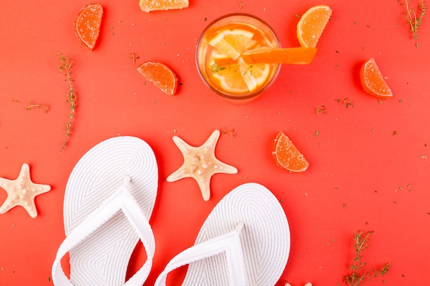 Orange fruit cocktail, detox water near white flip flops.