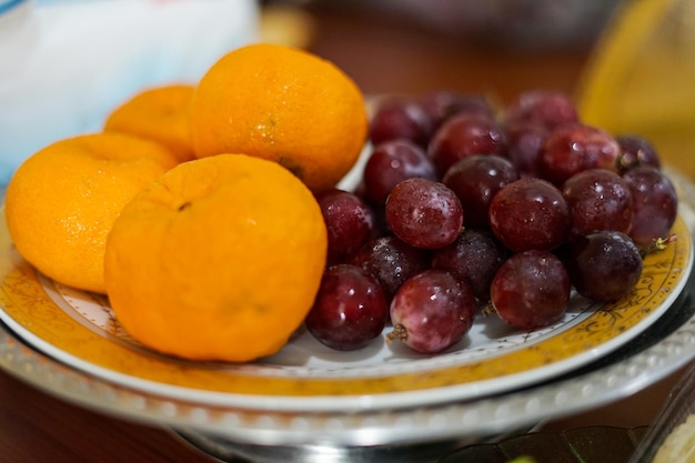 Orange fruit and fresh grapes on a plate on the table