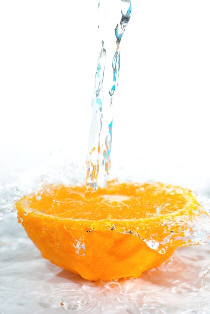 Mezza parte di frutta arancione con acqua isolato su sfondo bianco