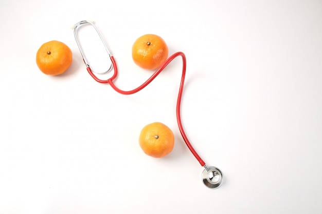 白地に赤い聴診器でオレンジ色の果物