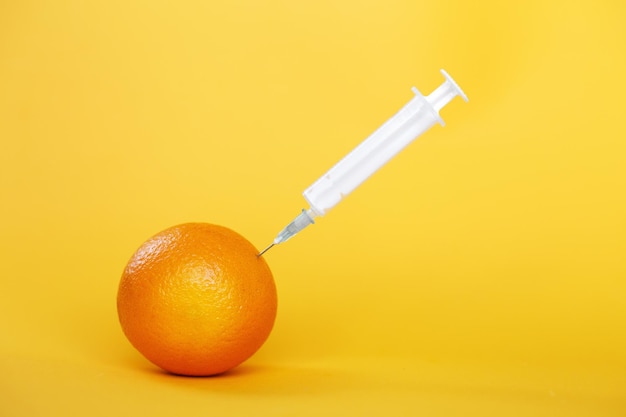 Orange fruit with syringe extracting liquid with vitamin C natural anti aging cosmetics concept