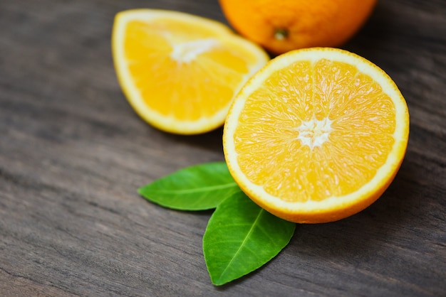 Orange fruit on wooden background - Fresh orange slice half and orange leaf healthy fruits harvest concept