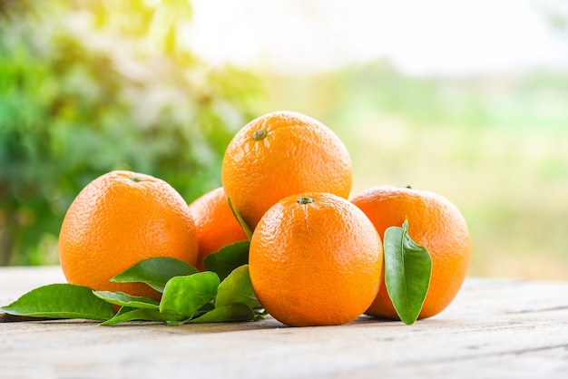 Фрукты апельсина с листьями на фоне деревянных и природы, свежий апельсин с листьями здоровые фрукты