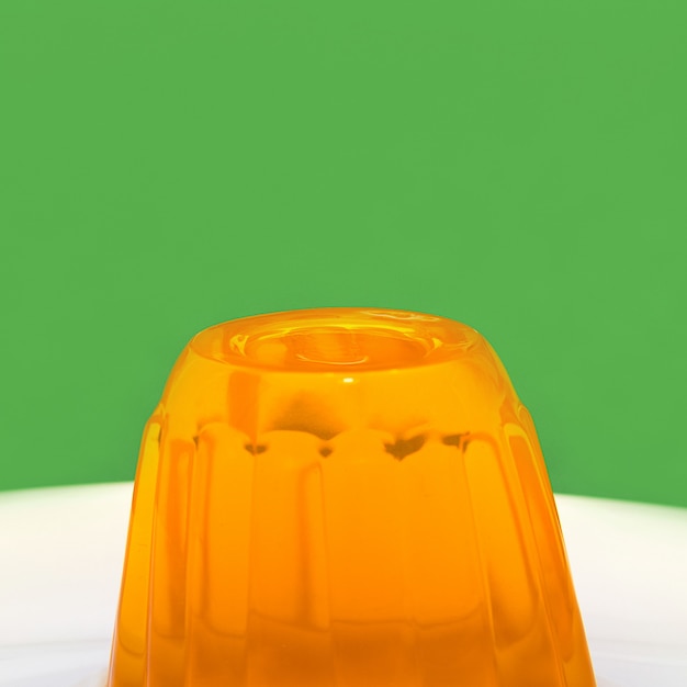 Orange gelatin on a white plate and green wall