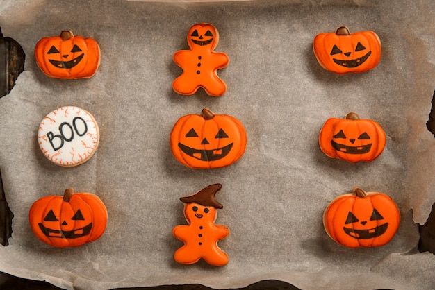 I biscotti arancioni allo zenzero per halloween giacciono su una carta da forno. biscotto a forma di zucca. vista dall'alto. biscotti deliziosi.