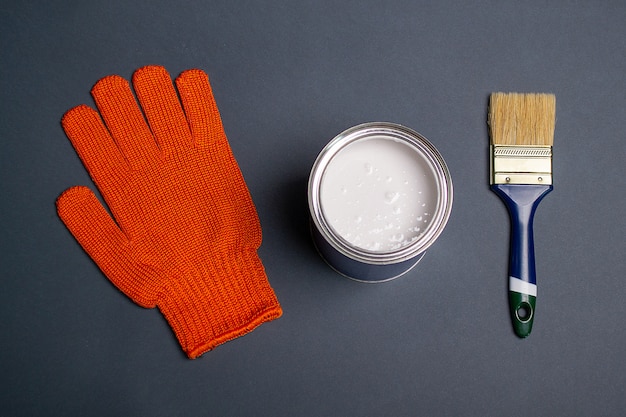 Orange glove next to a paint can and a paintbrush