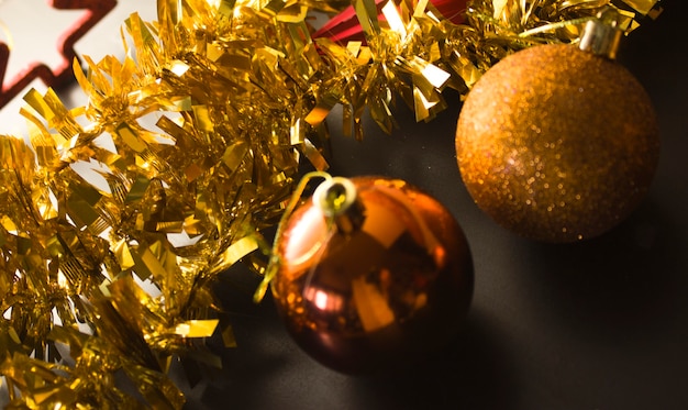 Orange gold shiny Christmas balls, gold garland in the background, back light