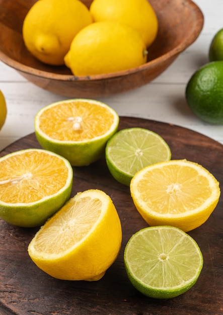 Orange, green lemon and sicilian lemon cuts over wooden board.