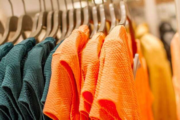 Orange and green shirts on hangers in shop