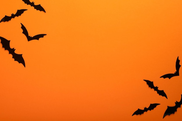 Orange Halloween background Flock of black bats for Halloween Black paper bat silhouettes on orange background Halloween concept Copy space top view overhead