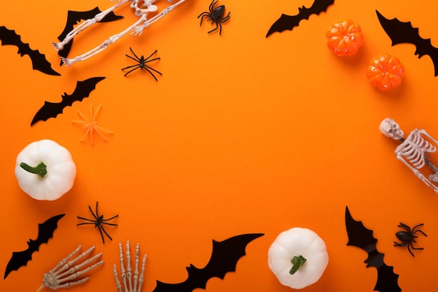 Orange Halloween background Flock of black bats spider pumpkin skeleton and leaves for Halloween Black paper bat silhouettes on orange background Autumn decoration Halloween concept Top view