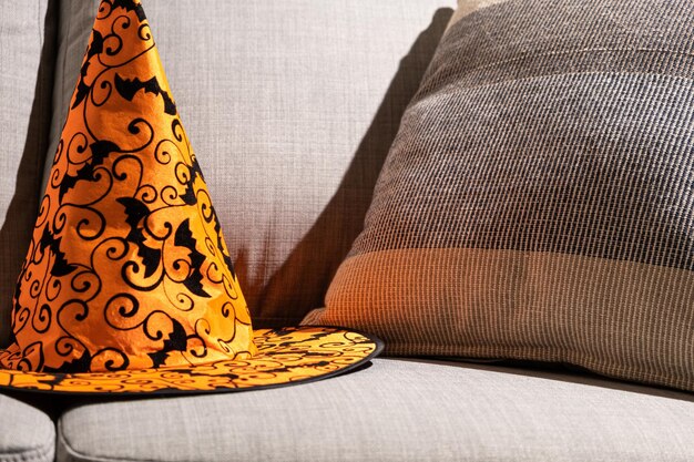 Orange Halloween hat on a gray sofa with a pillow Textiles and Halloween a place for text