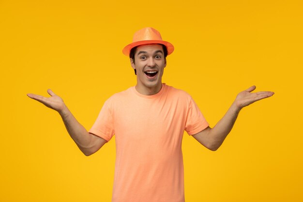 Orange hat cute young guy in orange shirt with the hat waving hands surprisingly