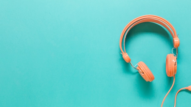 Orange headphones on colored surface