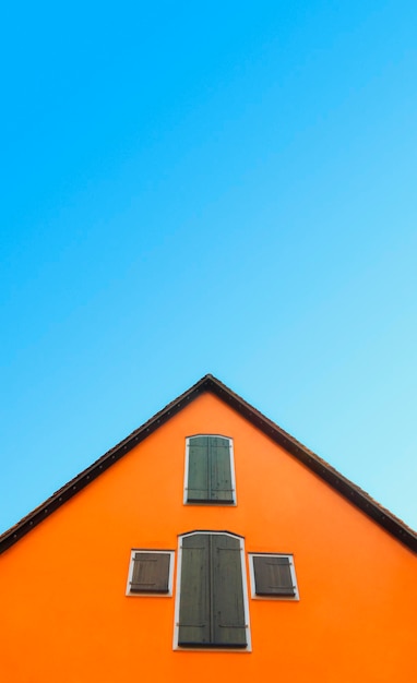 Orange house with pitched roof on a blue sky german home with orange walls and timber shutters