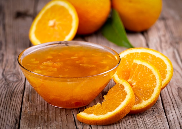 Orange jam in glass jar on wooden background