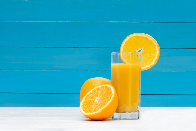 青い木製の背景にオレンジジュース