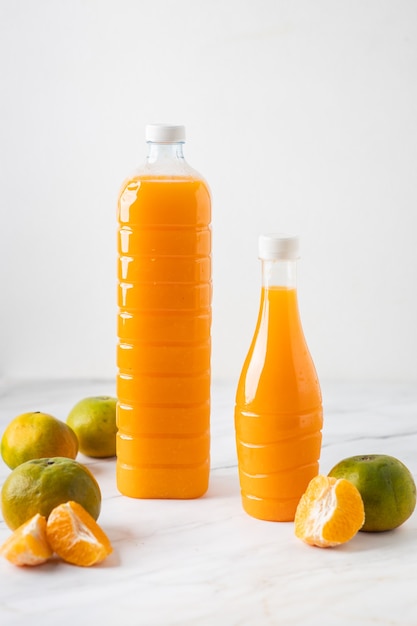 Foto succo d'arancia in bottiglia su marmo con arance