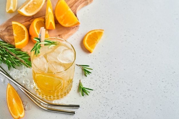 Succo d'arancia o cocktail con rosmarino e arancia con ghiaccio in vetro, limonata estiva fredda